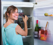 © JackF - adult girl arranging space of fridge shelves indoors