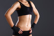 © lenets_tan - Muscular young woman  standing on gray background