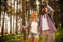 Young Couple Hiking Trough Forest And Watching Birds.Ornithology .