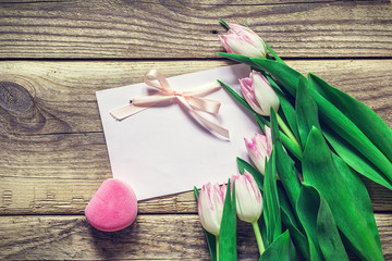 Blank card, pink tulips and gift box on a  grunge wooden backgro