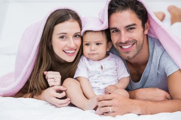 Wall Mural - Portrait of smiling couple with baby on bed 