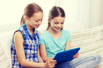 Poster - happy girls with tablet pc sitting on sofa at home