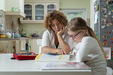 mother helping daughter with her homework at the table in the dinning room.