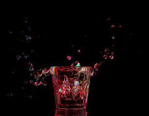 Wall Mural - Bright cocktail in glass and splashing water on dark background