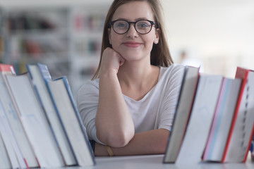 portrait of famale student selecting book to read in library