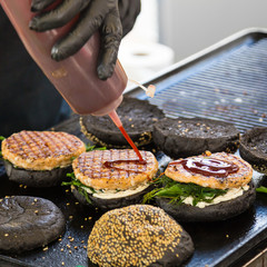 Wall Mural - Chef making beef burgers outdoor on open kitchen international food festival event. Street food ready to serve on a food stall.