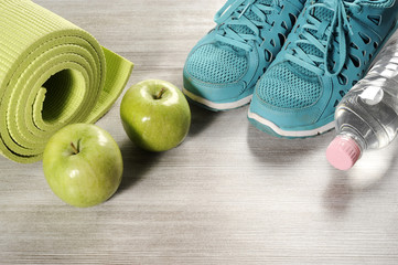 yoga mat with sport shoes and healthy food on a wooden background