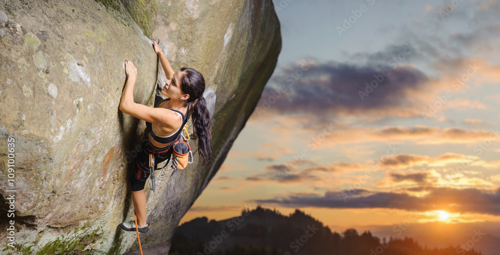 Young attractive female rock climber climbing challenging route on steep rock wall against scenic sunset background. Summer time. Climbing equipment - obrazy, fototapety, plakaty 