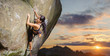 Young attractive female rock climber climbing challenging route on steep rock wall against scenic sunset background. Summer time. Climbing equipment