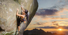 Young Attractive Female Rock Climber Climbing Challenging Route On Steep Rock Wall Against Scenic Sunset Background. Summer Time. Climbing Equipment