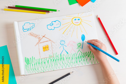 Fotografía Child draws a pencil drawing of the house and his family.