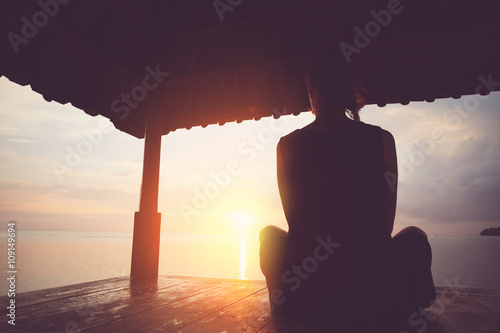 Plakat Kobieta cieszy się wschód słońca w słońce schronieniu, sylwetka. Vintage kolor i celowe światło słoneczne