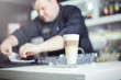 © 6okean - Barista prepares cappuccino in his coffee shop. Close-up cup of coffee.