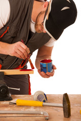 A carpenter pinting wood in red color isolated over white backgr