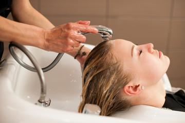 Hair stylist at work - hairdresser washing hair to the customer