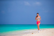 © travnikovstudio - Fit young woman running along tropical beach in her sportswear