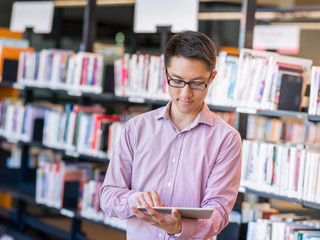 Happy male student holding books at the library