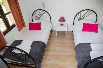 Top view of two grey beds with pink cushion.