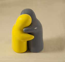 two colored porcelain figurines of people hugging yellow brown