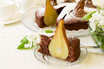 Piece of homemade chocolate cake with pears decorated pear blossom