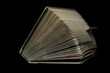 Stara książka z lekko rozchylonymi stronicami na ciemnym tle w naturalnym oświetleniu. Ujęcie od góry-przodu.Widoczna wystająca zakładka