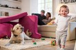 © Connect Images - Baby boy and pet dog playing in fort made from sofa cushions, looking at camera smiling