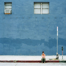 Woman Sitting In Front Of Blue Building