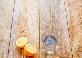 glass of fresh water with halved lemon on wooden table