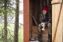 Woman Sitting In Wooden Outhouse