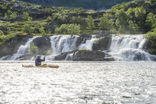 Man Kayaking Near Waterfall
