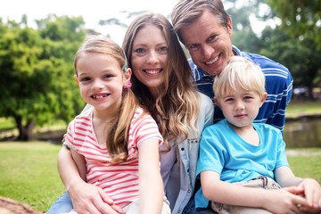 Wall Mural - Happy family sitting together in the park