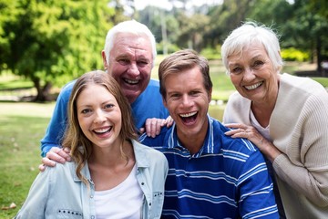 Wall Mural - Portrait of happy family sitting together in the park