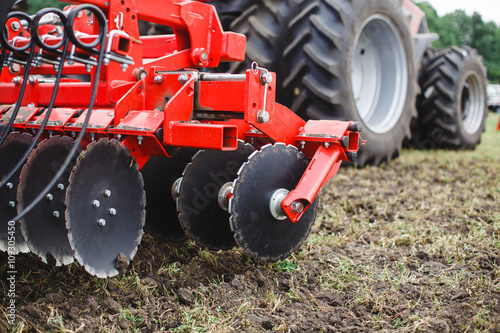 Foto Plow modern tech red tractor close up on an agricultural field Mechanism