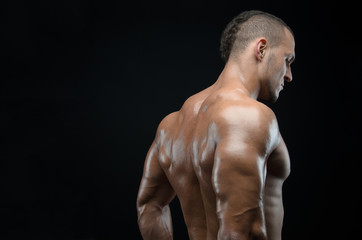 Bodybuilder and strip theme: beautiful with pumped muscles naked man posing in the studio on a dark background