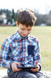 © sakkmesterke - Little boy playing on tablet outdoor