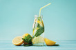 Lemonade drink of soda water, lemon and mint leaves in jar on turquoise background