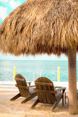 Wall Mural - Beach resort scene with tropical grass hut and chair with ocean and sand