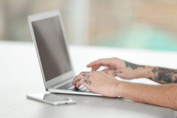 Poster - Young man with tattoo using laptop at the table