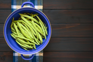 Wall Mural - Green beans in blue metal strainer, photographed on dark wood with natural light