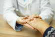Doctor holding hand of elderly woman