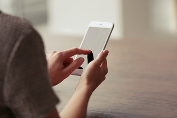 woman's hands using mobile phone at the table