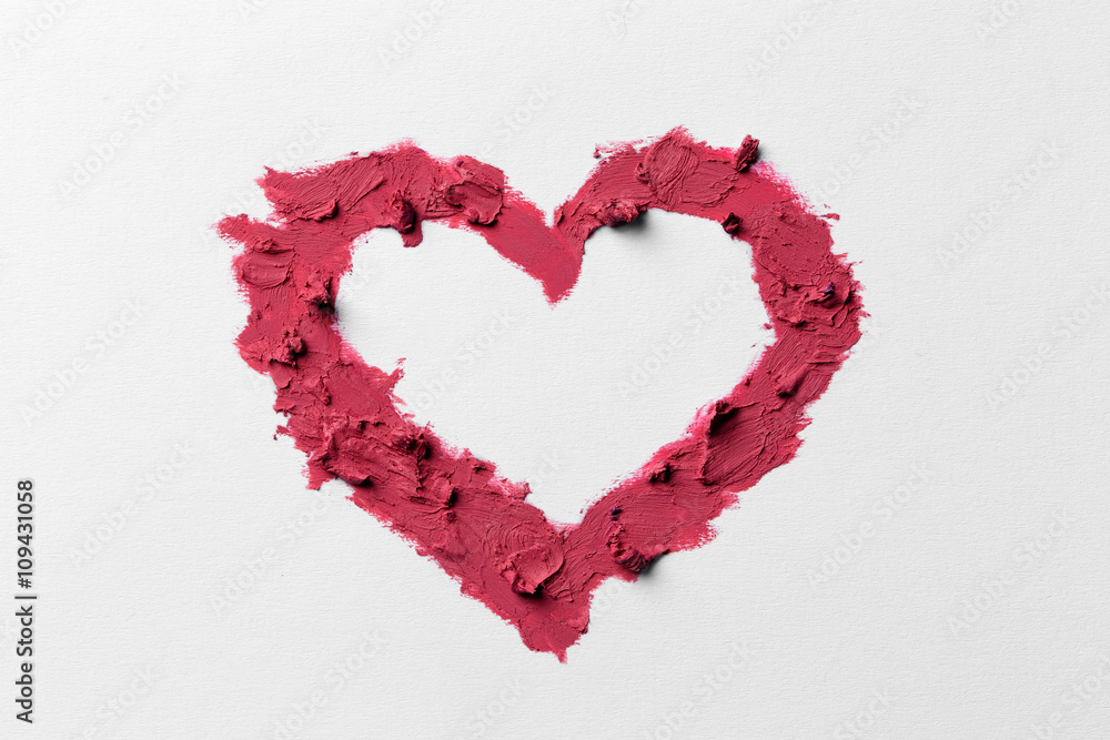 Pink lipstick smeared in heart shape isolated on white background, close up