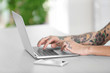 © Africa Studio - Young man with tattoo using laptop at the table