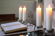 Altarraum mit Bibel, Kreuz und brennenden Kerzen