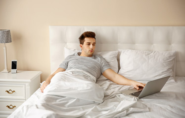 Wall Mural - Man lying in bed with his laptop