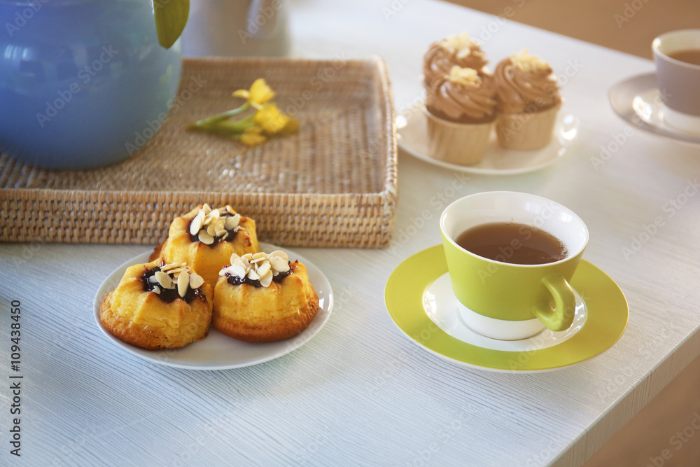 Cups of tea and cakes on wooden background