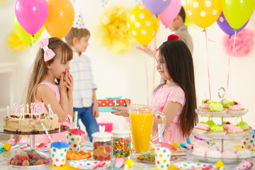 Wall Mural - Happy little girl presenting a gift to her friend at birthday party