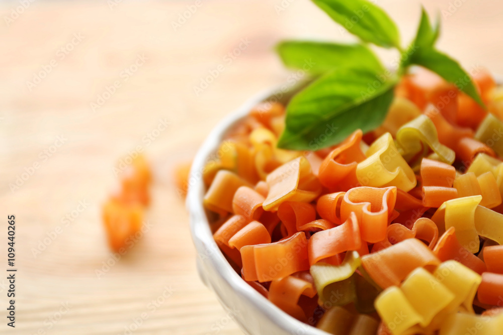 Dry multicolored heart shaped pasta in white bowl, close up