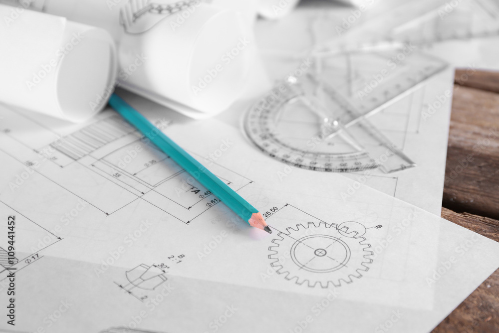 Set of engineering drawings with tools on wooden table closeup