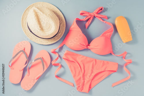Fotografie, Obraz Pink swimsuit with beach accessories on blue background